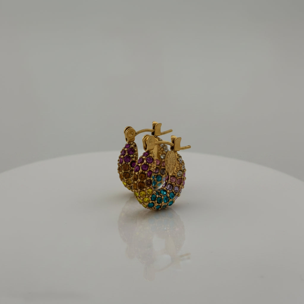 Gold hoop earrings with multicolored gemstones on a gray background