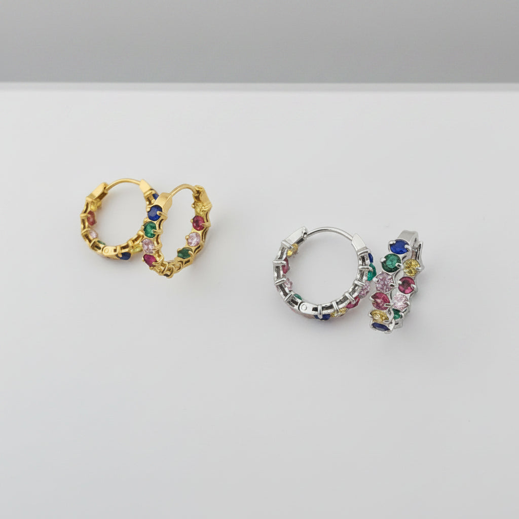 Two rings, one gold and one silver, with colorful gemstones on a gray background.