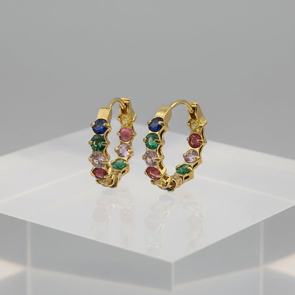 Gold hoop earrings with multicolored gemstones on a gray background