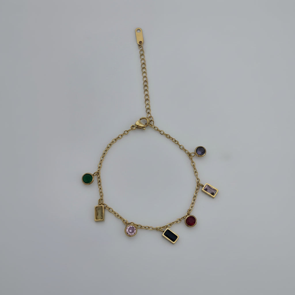 Gold bracelet and necklace with gemstone charms on a light gray background