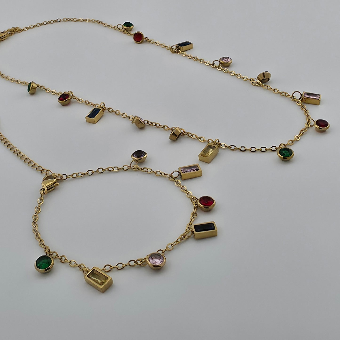 Gold necklace with gemstone pendants on a light gray background
