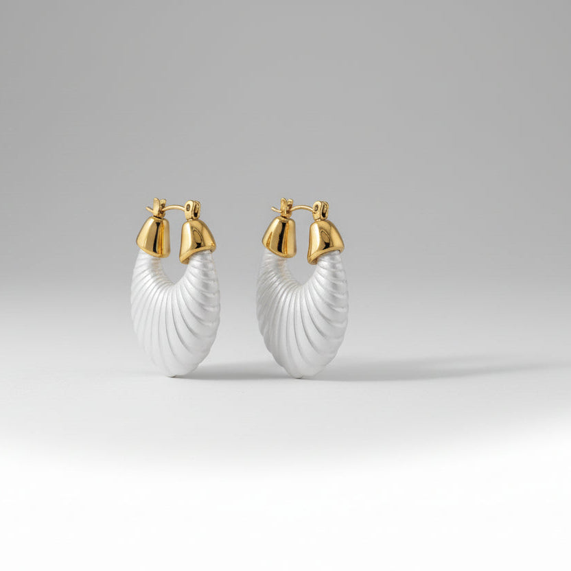 Pair of white hoop earrings with gold accents on a light gray background