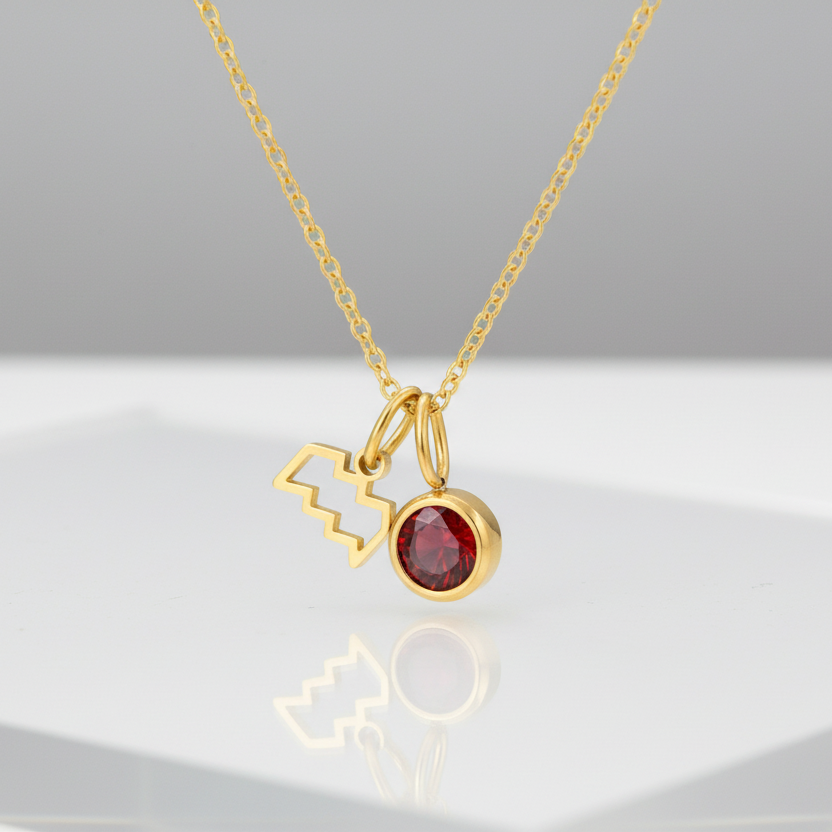 Gold necklace with a red gemstone pendant on a white background