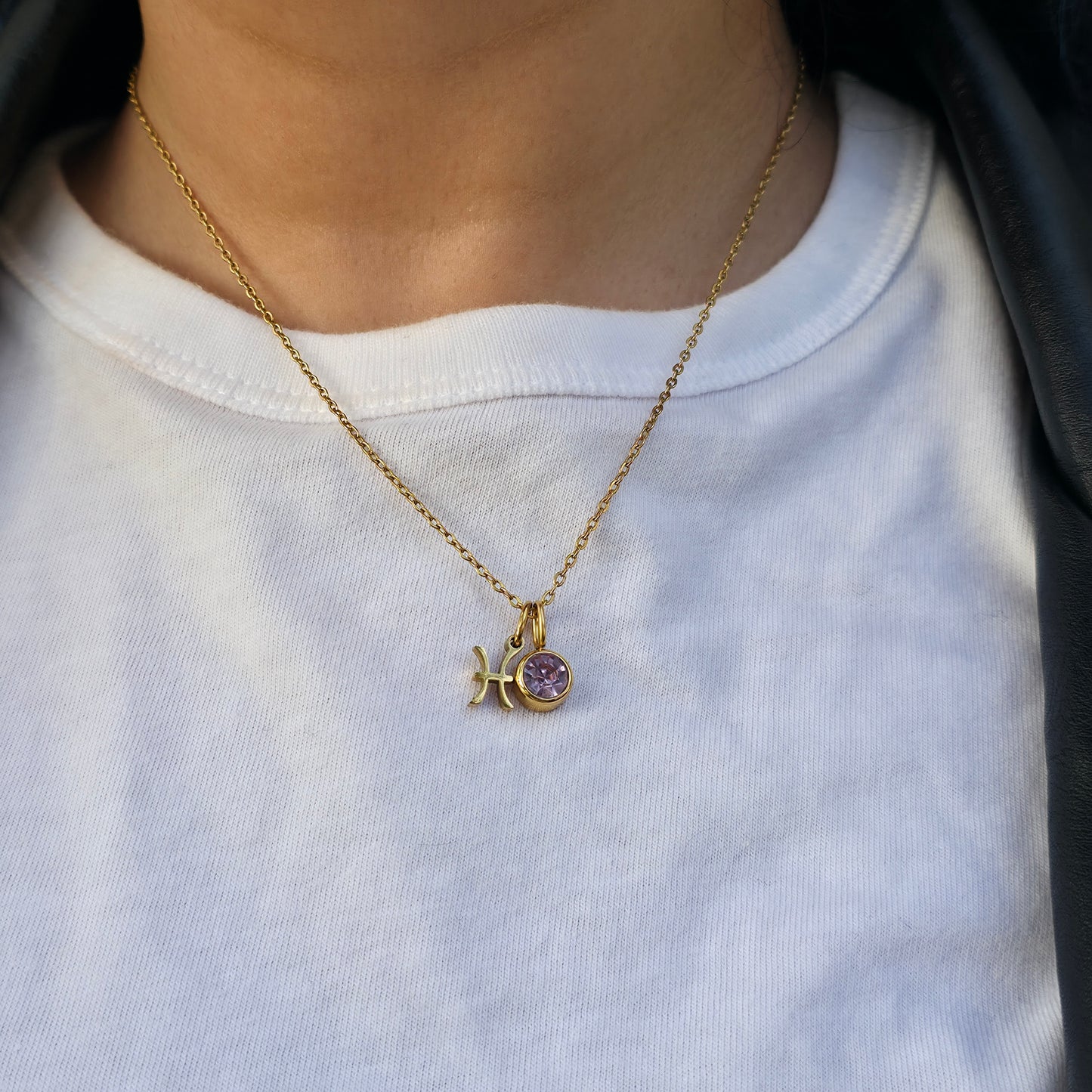 Gold necklace with a purple pendant on a white shirt