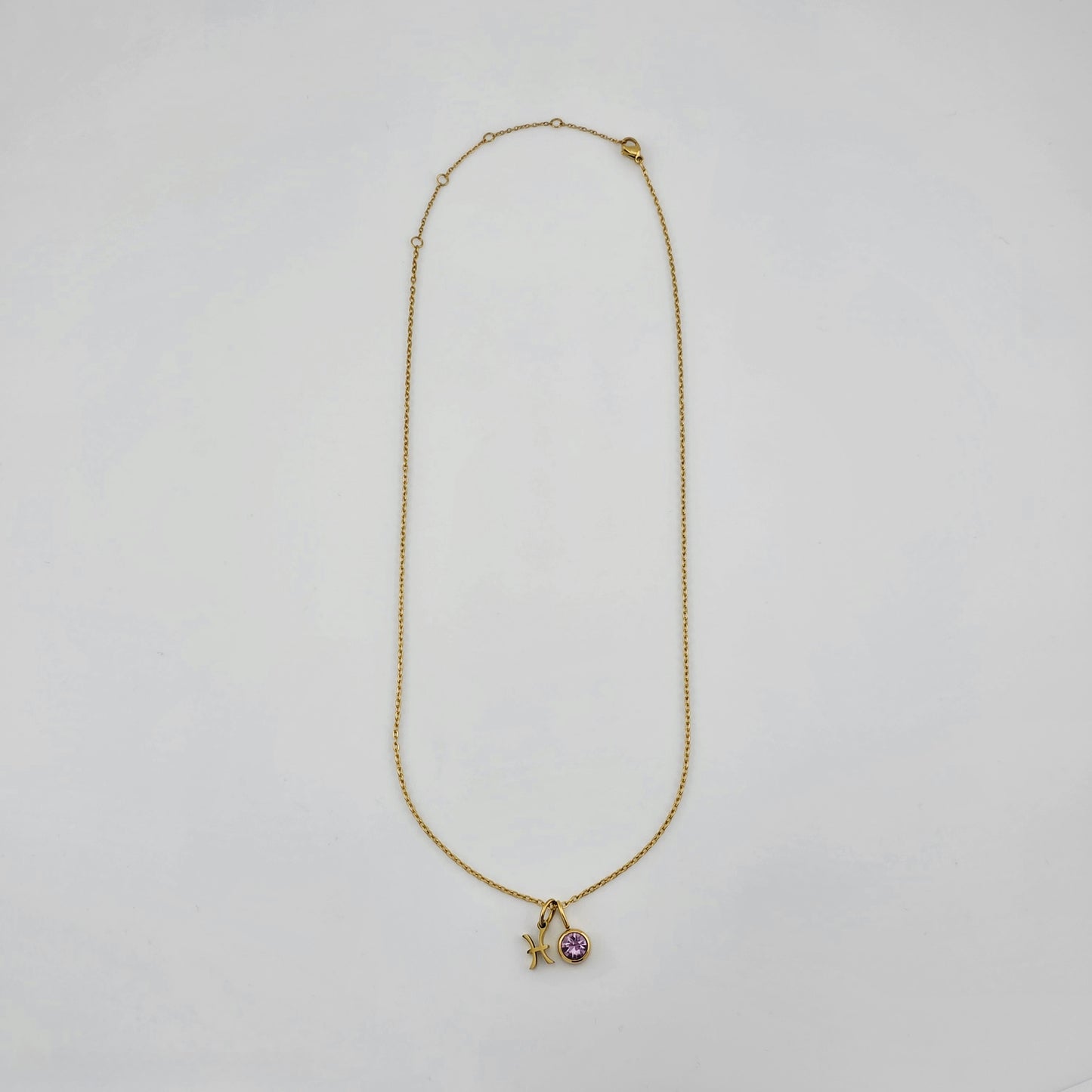 Gold necklace with a starfish and heart pendant on a light gray background