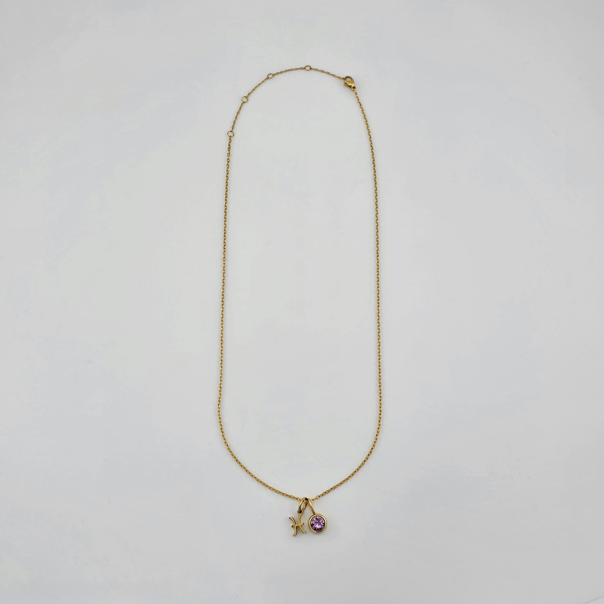 Gold necklace with a starfish and heart pendant on a light gray background