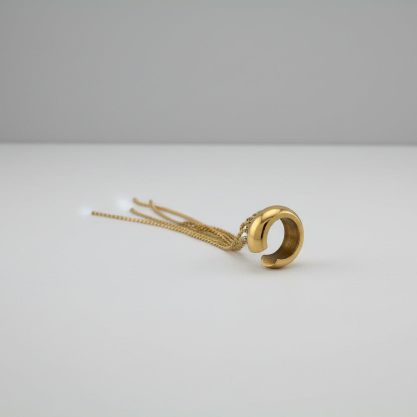Gold earring with dangling elements on a white platform