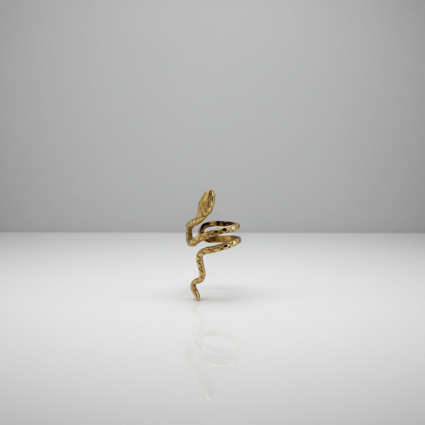 Gold snake-shaped earring on a gray stand with a white background