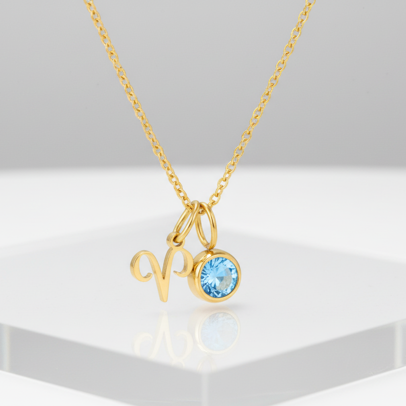 Gold necklace with an Aries pendant and a blue gemstone on a white background