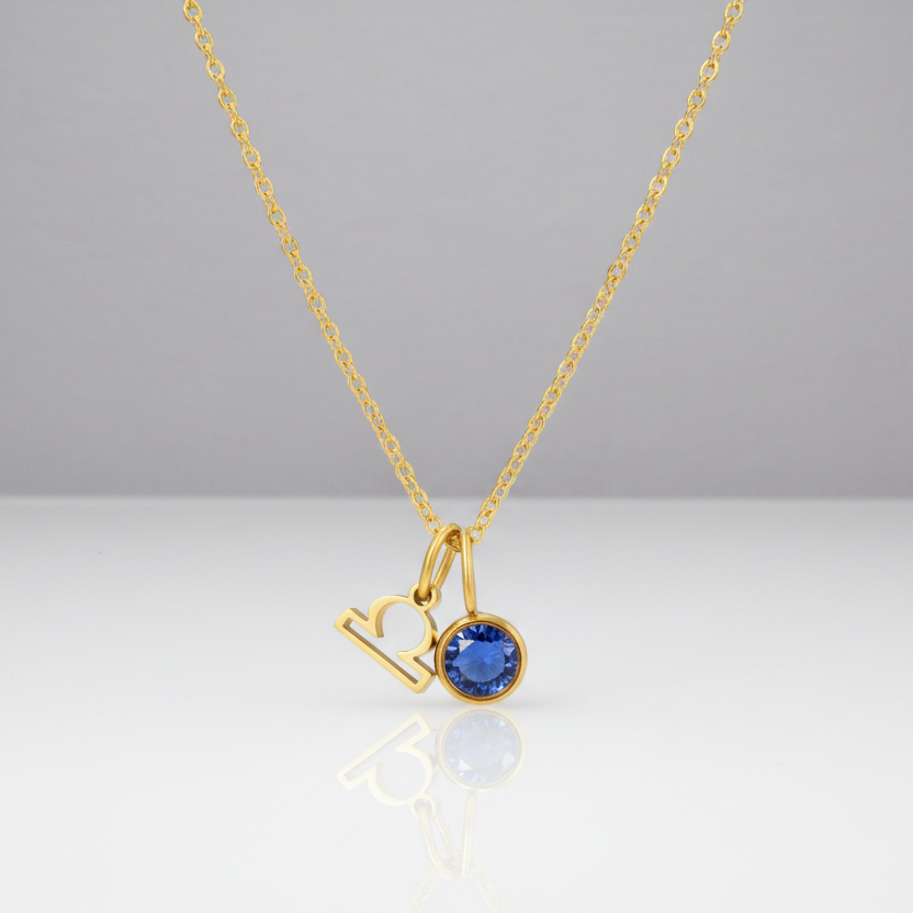 Gold necklace with a blue gemstone pendant on a white background