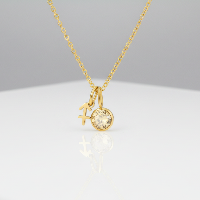 Gold necklace with a zodiac sign pendant and clear gemstone on a white background