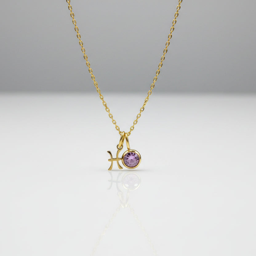 Gold necklace with a starfish and purple gemstone pendant on a light gray background