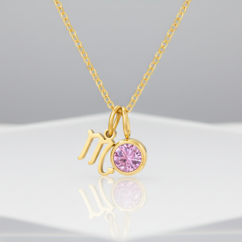 Gold necklace with 'MO' charm and pink gemstone on a white background