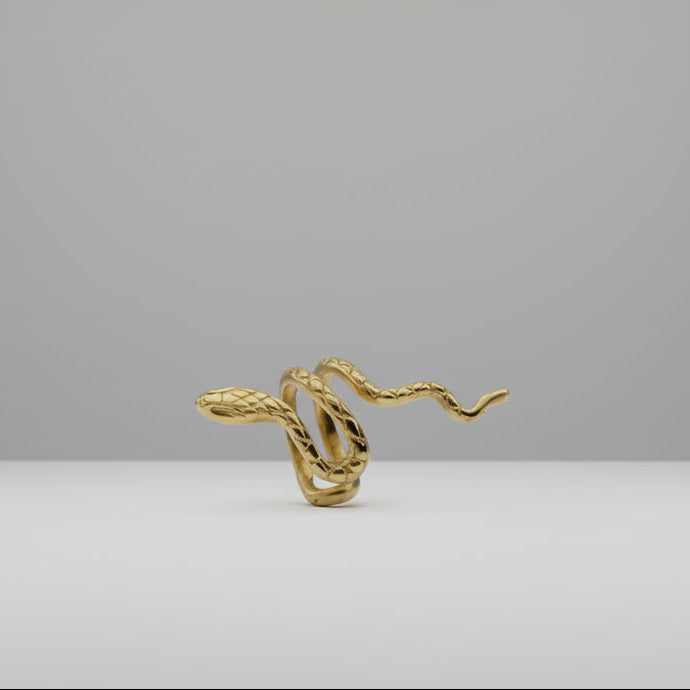 Gold snake-shaped earring on a white stand with 'AI-generated content' label.
