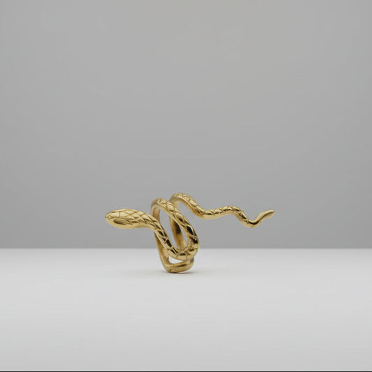 Gold snake-shaped earring on a white stand with 'AI-generated content' label.